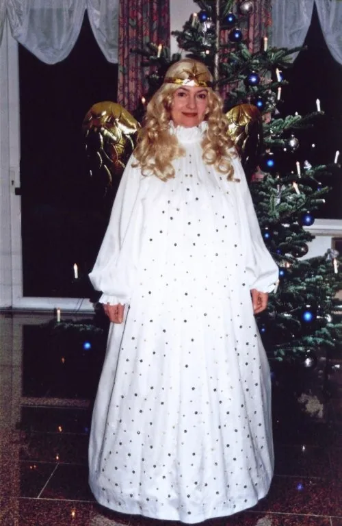 Sängerin im Engelskostüm vor einem Weihnachtsbaum.