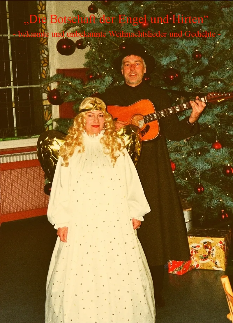 Wera als Engel und Bernd als Hirte mit Gitarre vor einem Weihnachtsbaum.