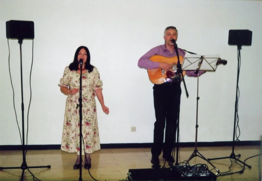Wera und Bernd bei einem Bühnenauftritt mit Mikrofonen und Gitarre.